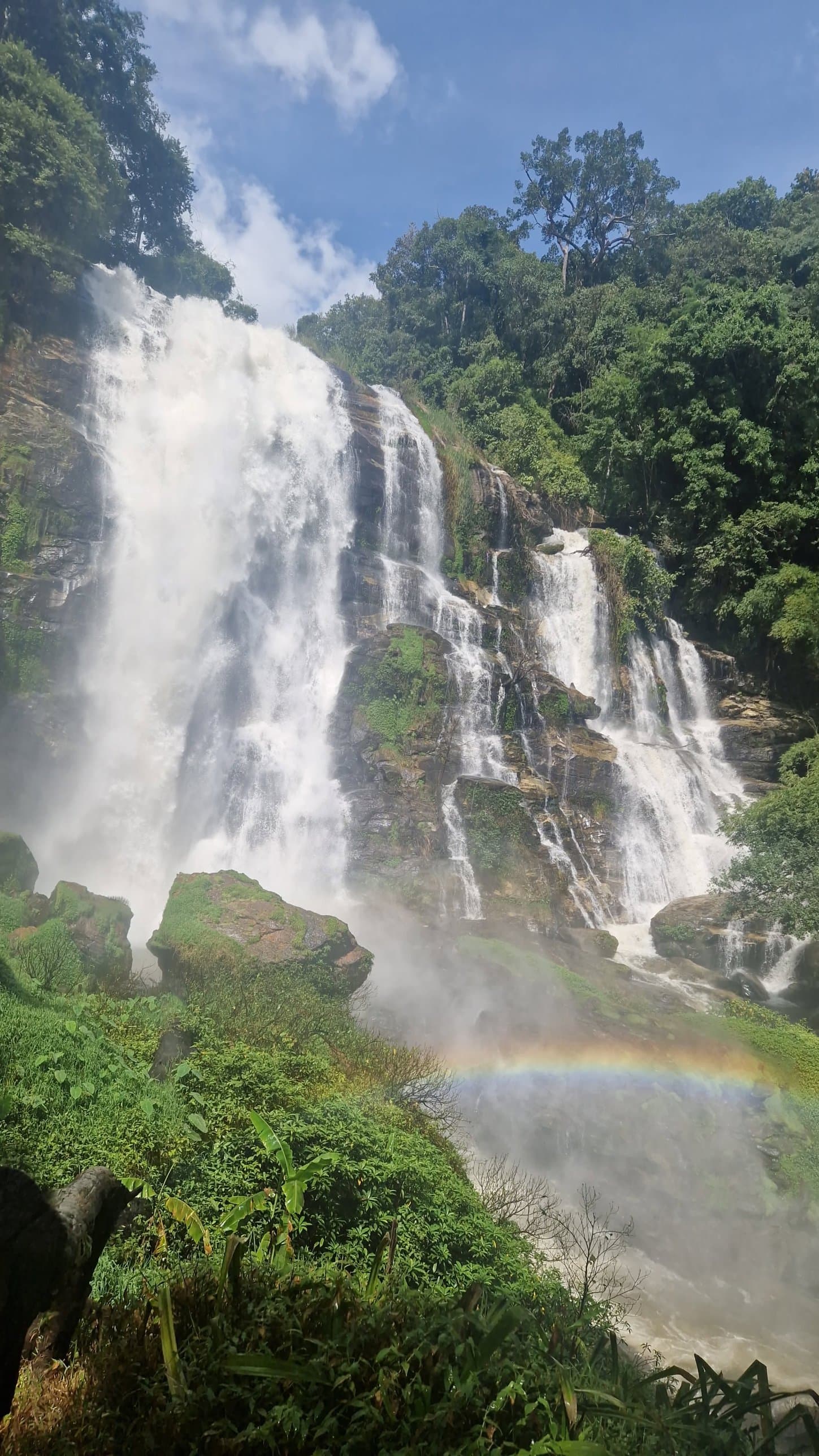 A tall waterfall in northern Thailand with a rainbow in the spray
